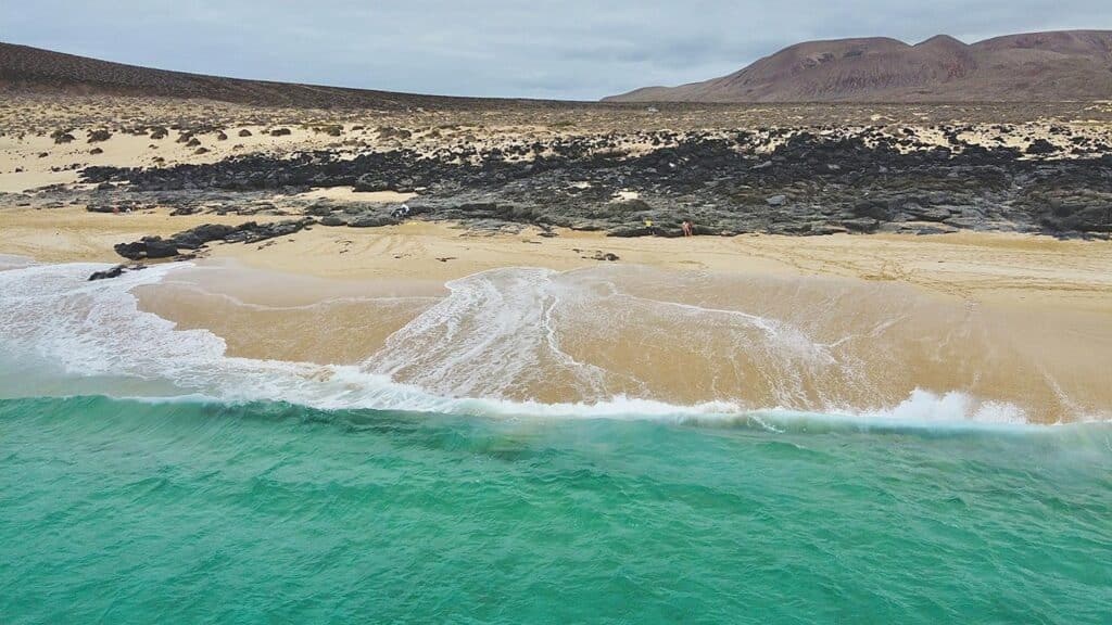 Playa de las Conchas i La Graciosa, med sandstrand och klarblått vatten.