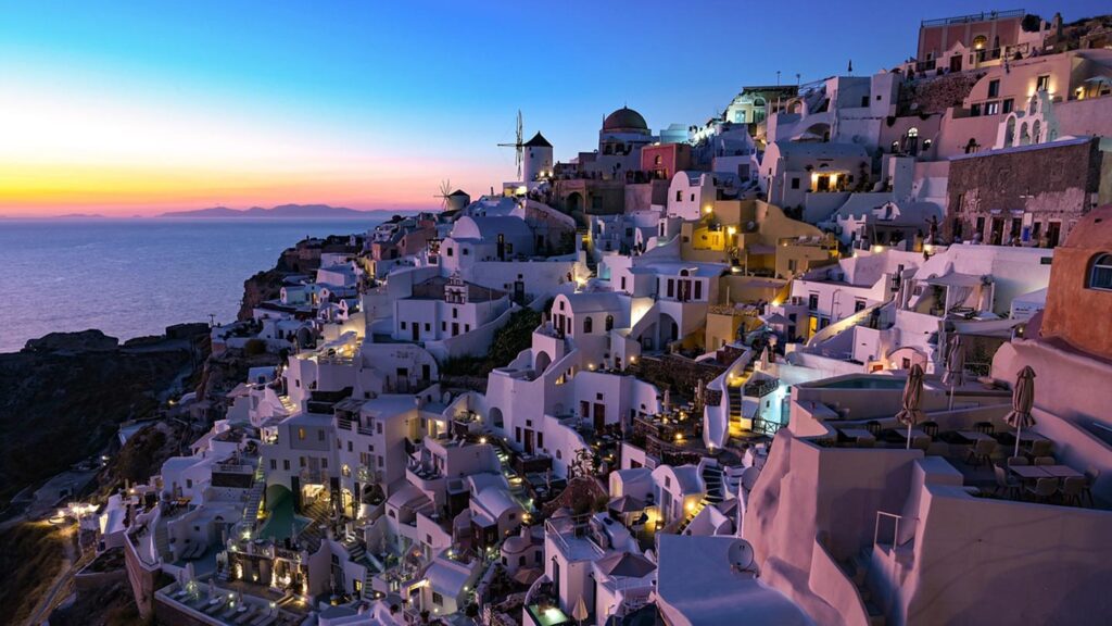 Solnedgång över Santorini i Grekland, med vackra vita byggnader och havet i bakgrunden.
