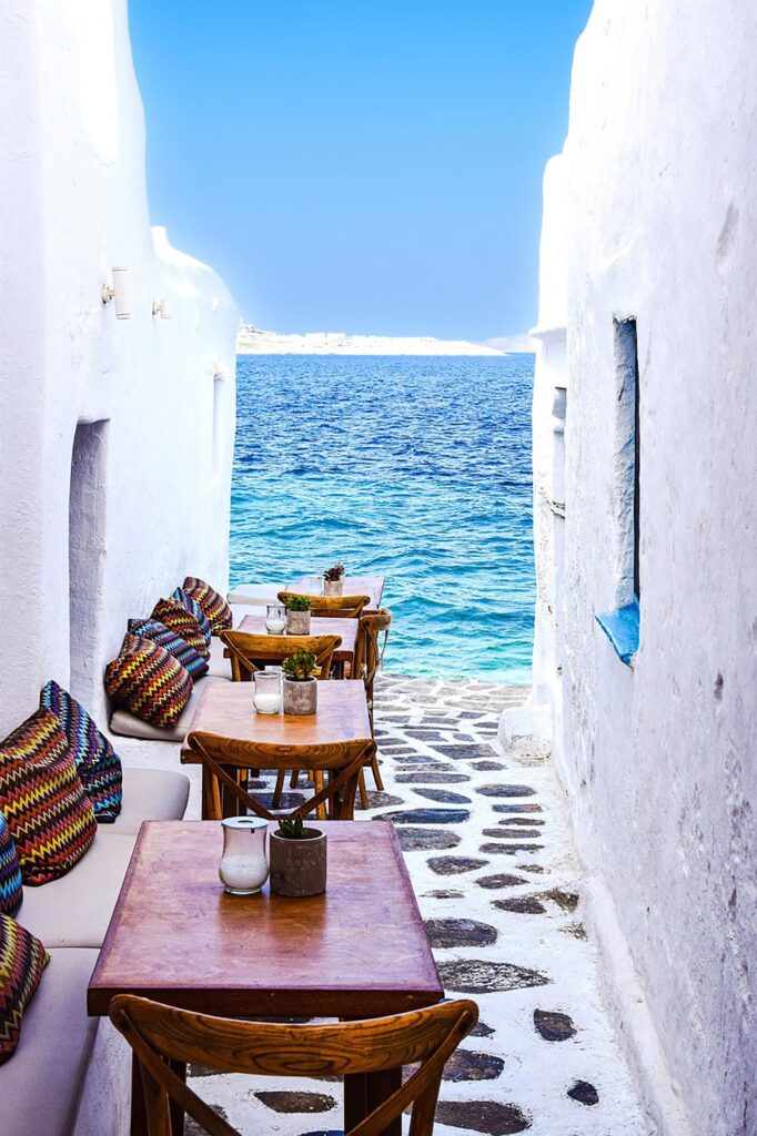 En vacker vy vid havet i Mykonos med träbord och färgglada kuddar.