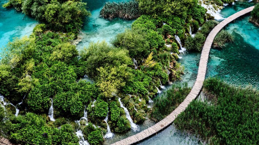 Gröna vattenfall i Plitvicesjöarnas nationalpark omges av frodig natur och turkost vatten.