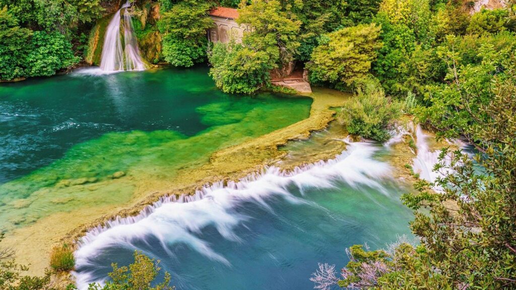 Krka nationalpark i mellersta Dalmatien, med grönskande vattenfall och klart vatten.
