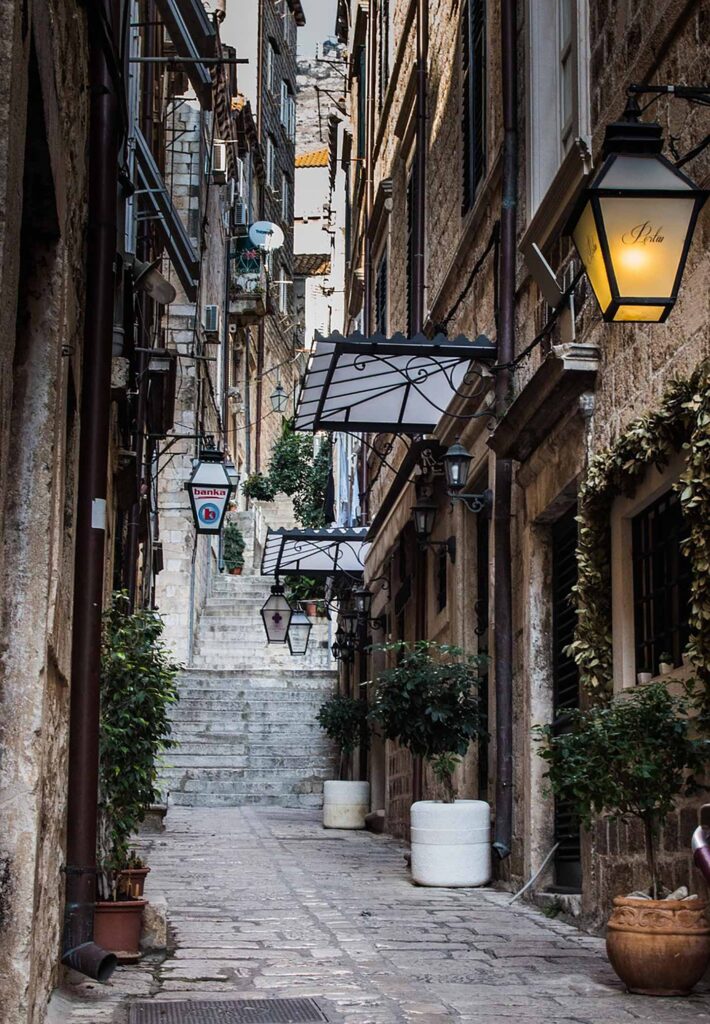 En mysig gränd med gamla stenhus i Dubrovnik, Kroatien. Lanternor och växter pryder gatan.