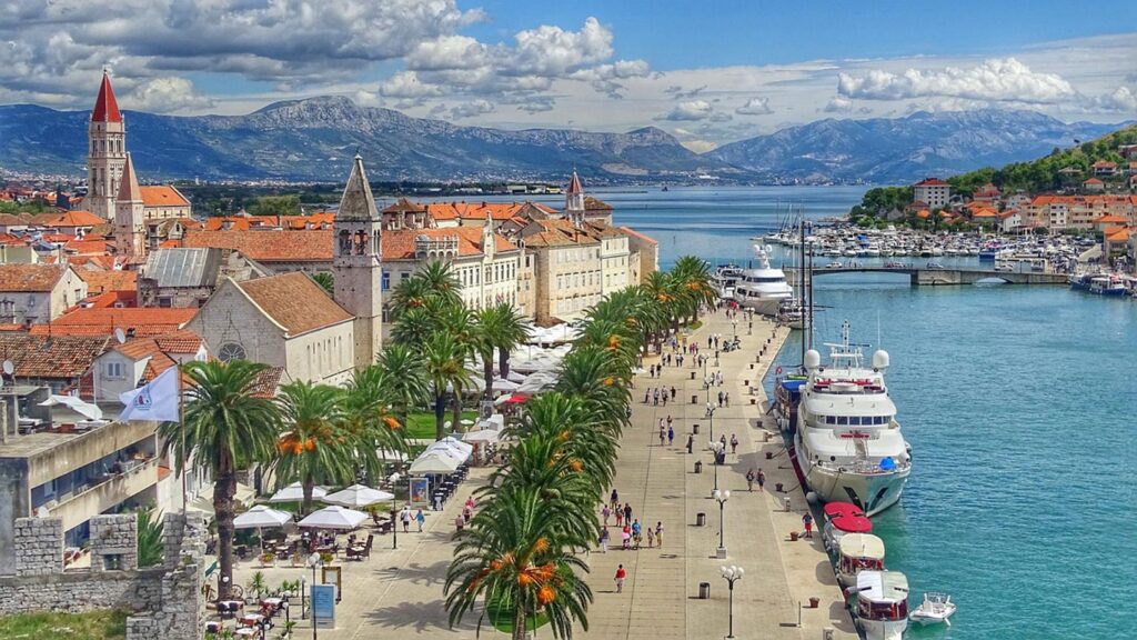 En vacker promenad längs hamnen i Trogir, Dalmatien, med palmer och båtar.