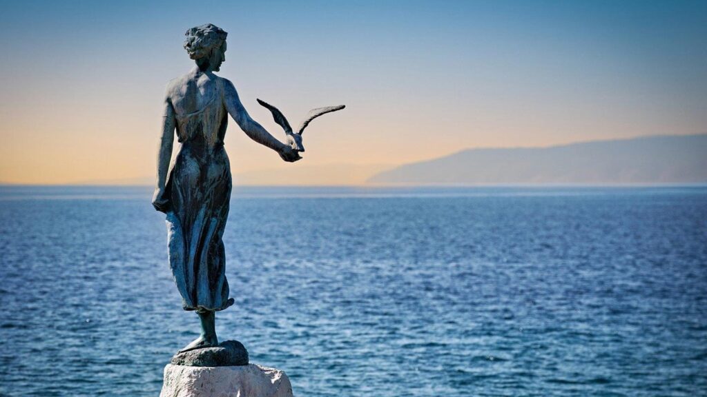 En staty vid havet i Opatija, Kroatien, med vacker havsutsikt.