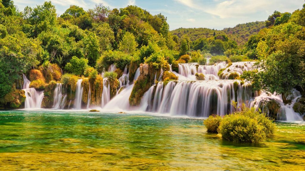 Vattenfall i Krka nationalpark, omgiven av grönska och klarhet i vattnet.