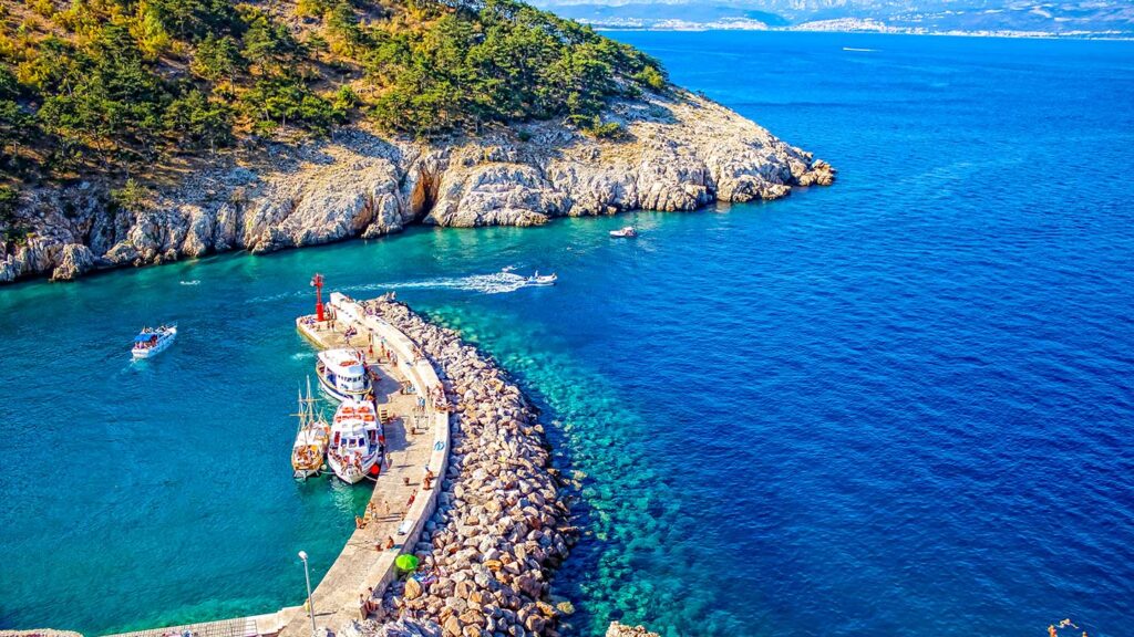 Bilden visar viken i Opatija, Kroatien, med båtar och klart, blått vatten.