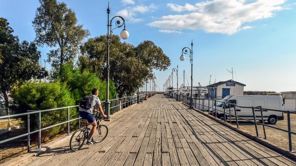 En cyklist färdas längs piren i Larnaca, Cypern, under klara himmel.