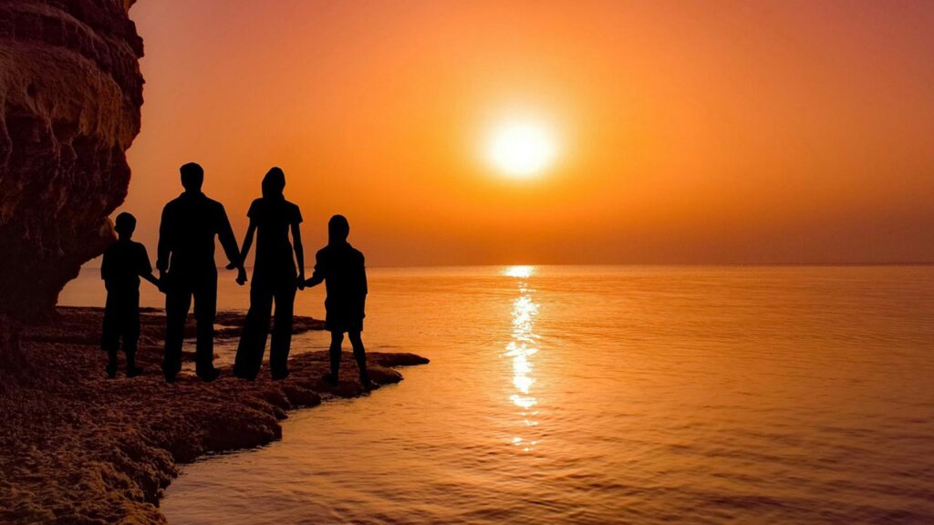 Familj håller varandra i handen vid solnedgången i Cavo Greko, Ayia Napa, Cypern.