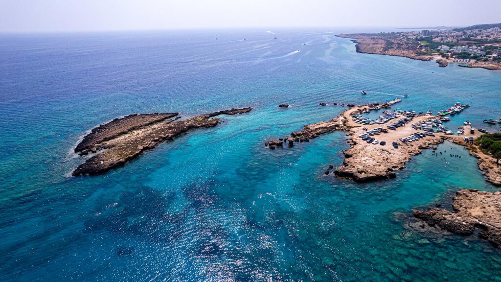 Flygfoto över Ayia Napa i Cypern med klart turkost vatten och klippor.