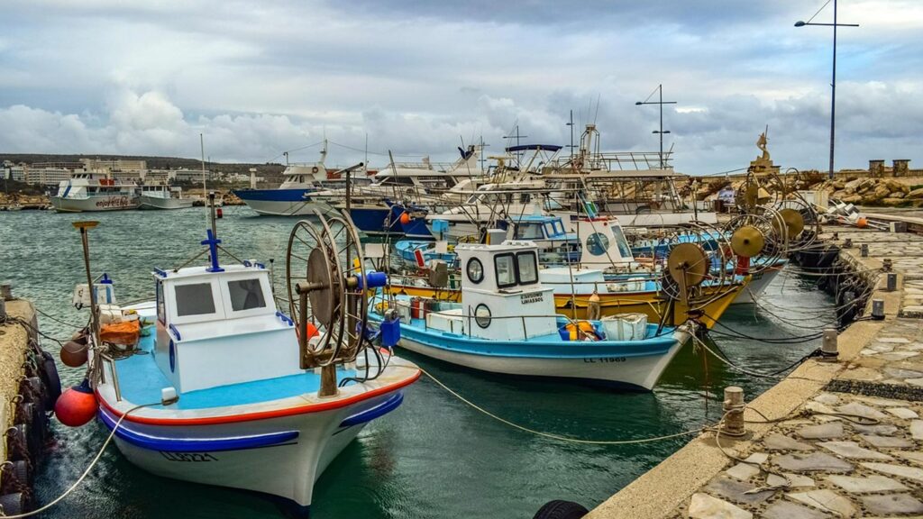 Båtar ligger vid hamnen i Ayia Napa, Cypern, omgiven av molnig himmel.