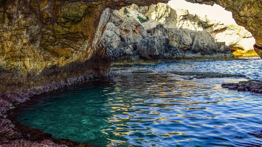 En havsgrotta med en naturlig pool i Ayia Napa, Cypern. Klippigt landskap och klart vatten.