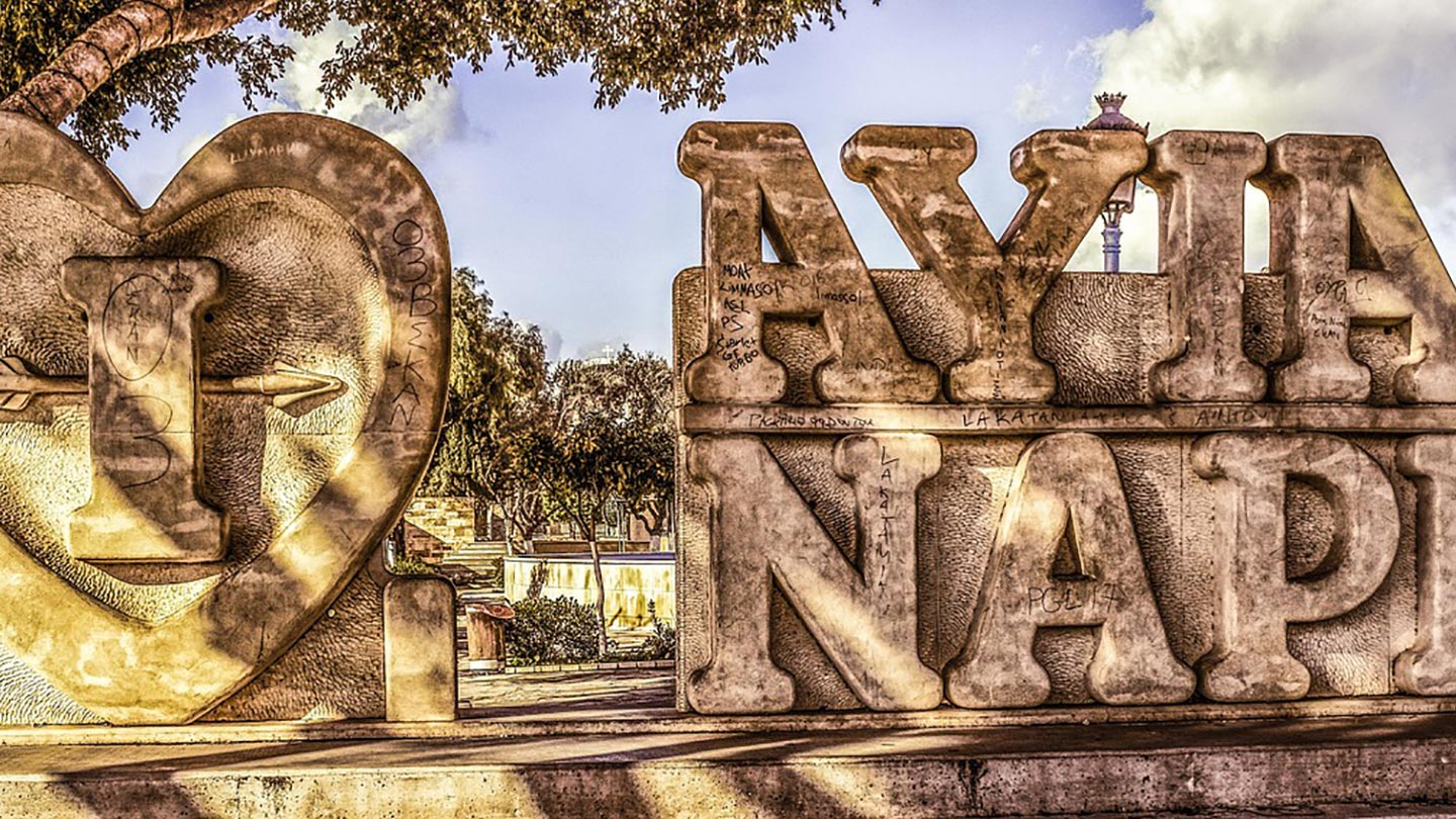 Skulpturen "I Love Ayia Napa" i Ayia Napa, Cypern, med trädsdäck i bakgrunden.