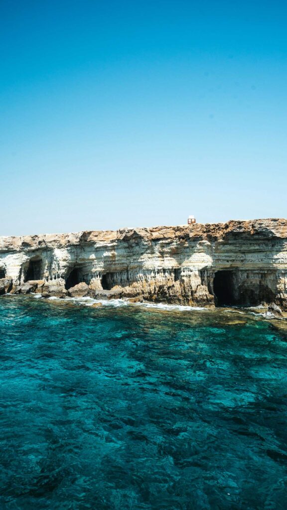 En klippig kust med klart turkost vatten vid Kap Greco, Ayia Napa, Cypern.