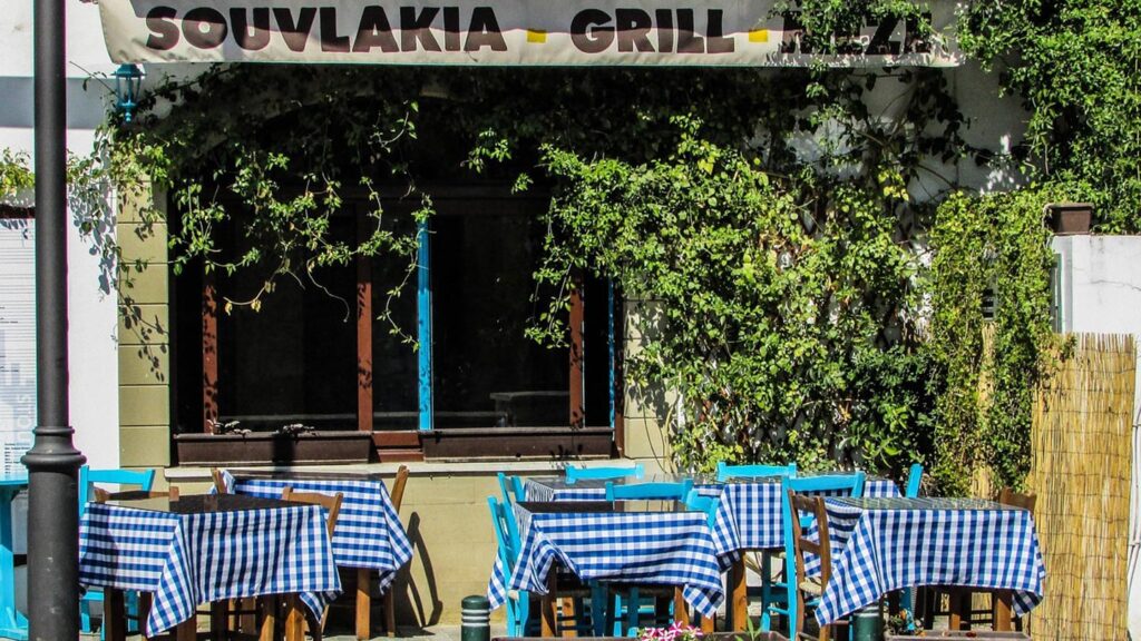 En krog i Larnaca, Cypern, med blå rutiga dukar och grönskande omgivning.