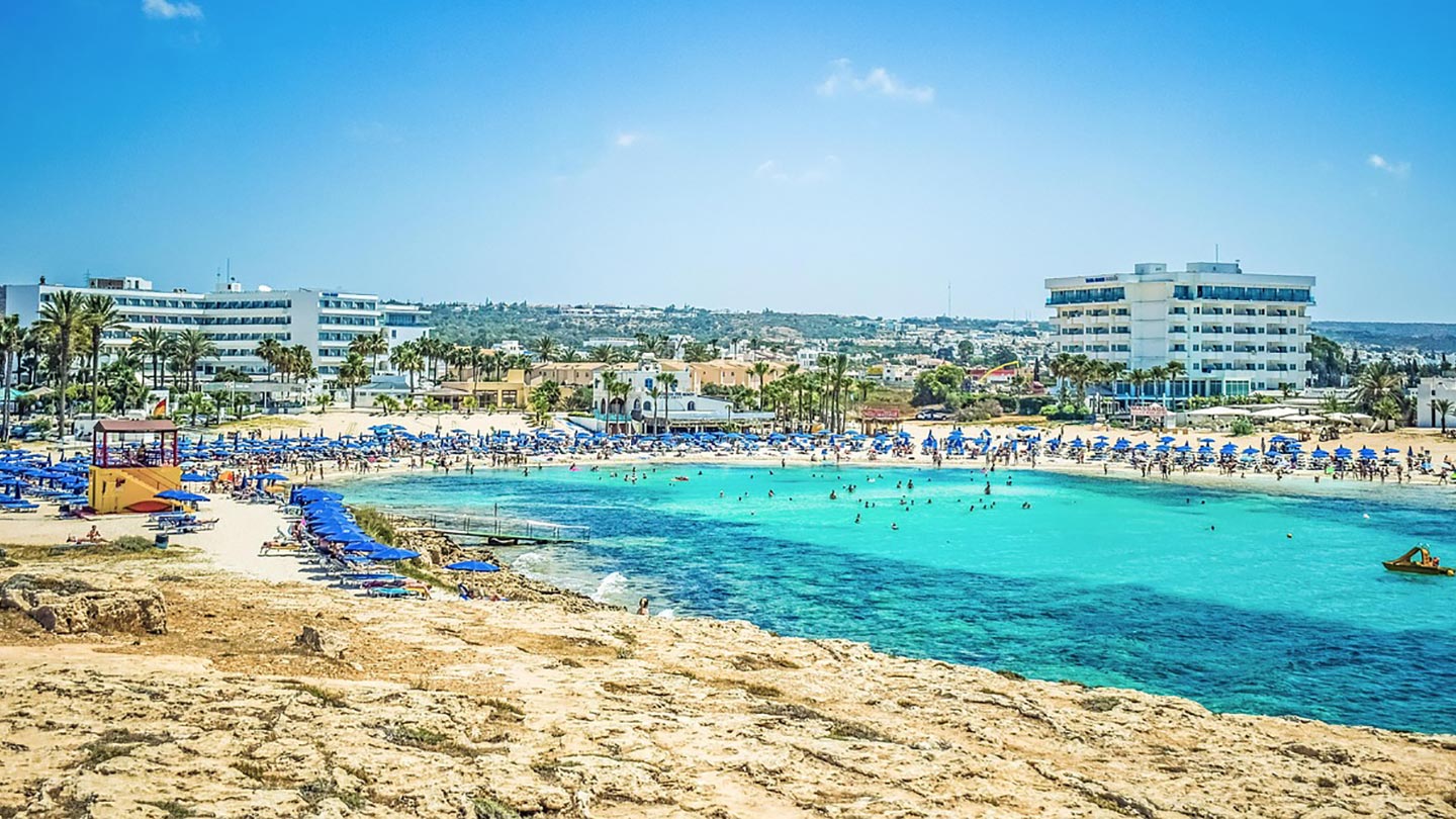 Nissi Beach i Ayia Napa, Cypern, med turkost vatten och många solstolar.