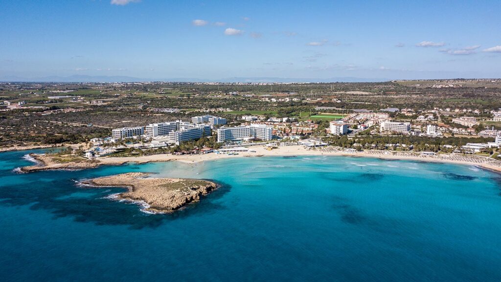 Nissi Beach i Ayia Napa, med klart turkost vatten och hotell vid kusten.
