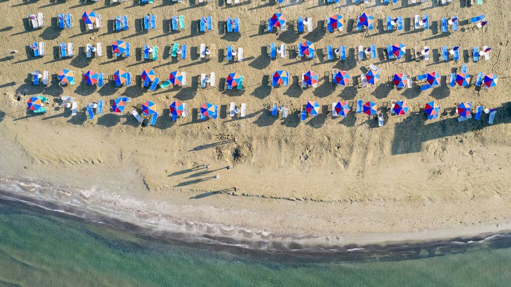 En strand i Larnaca, Cypern, med färgglada parasoller och solstolar.