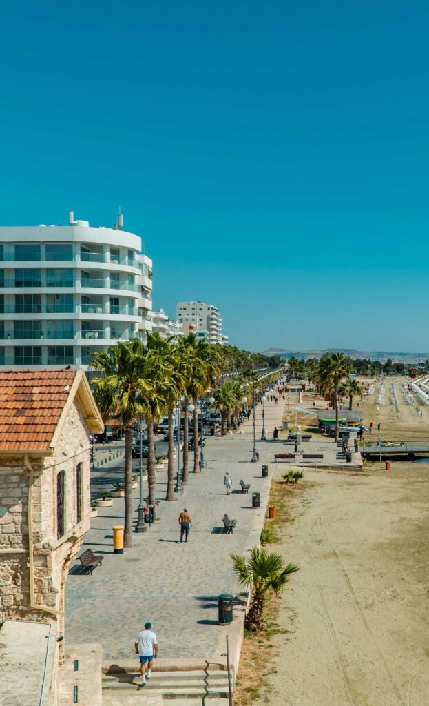 En solig dag vid Finikoudesstrand i Larnaca, med palmer och promenad.