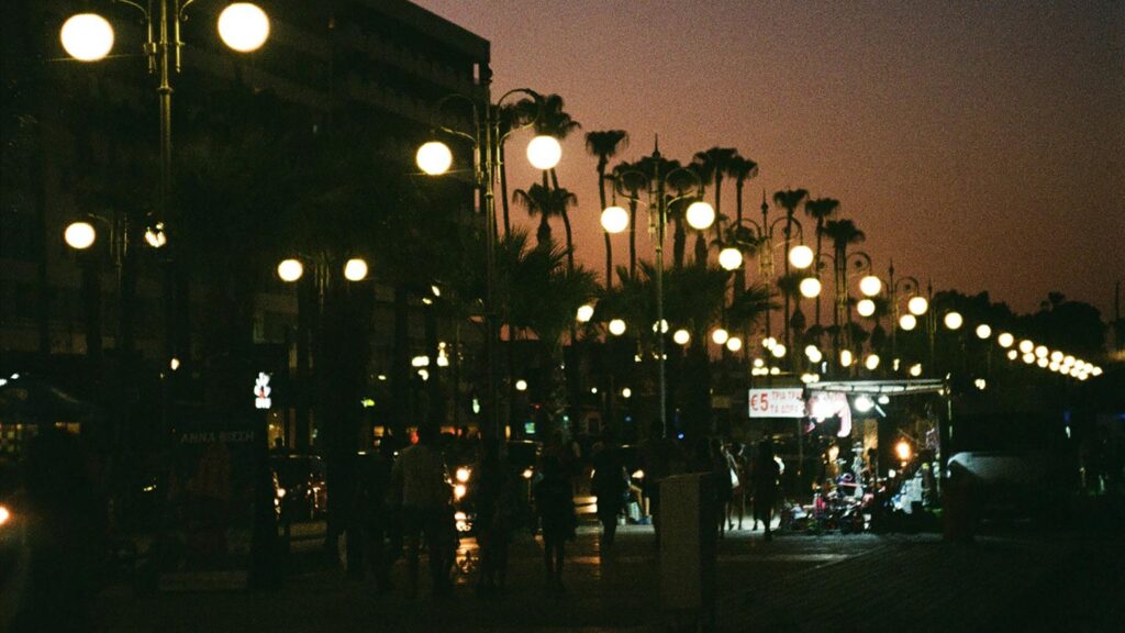Finikoudesstranden i Larnaca, Cypern, belyst av lampor på natten.