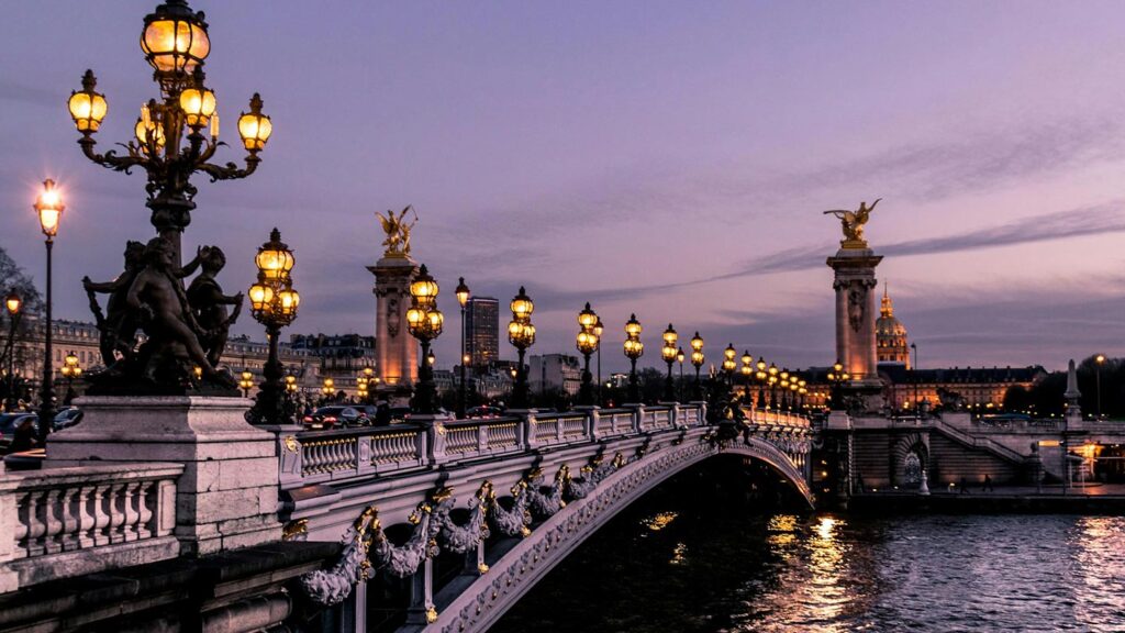 Pont Alexandre III i Paris lyser vackert vid skymningen med eleganta lampor.