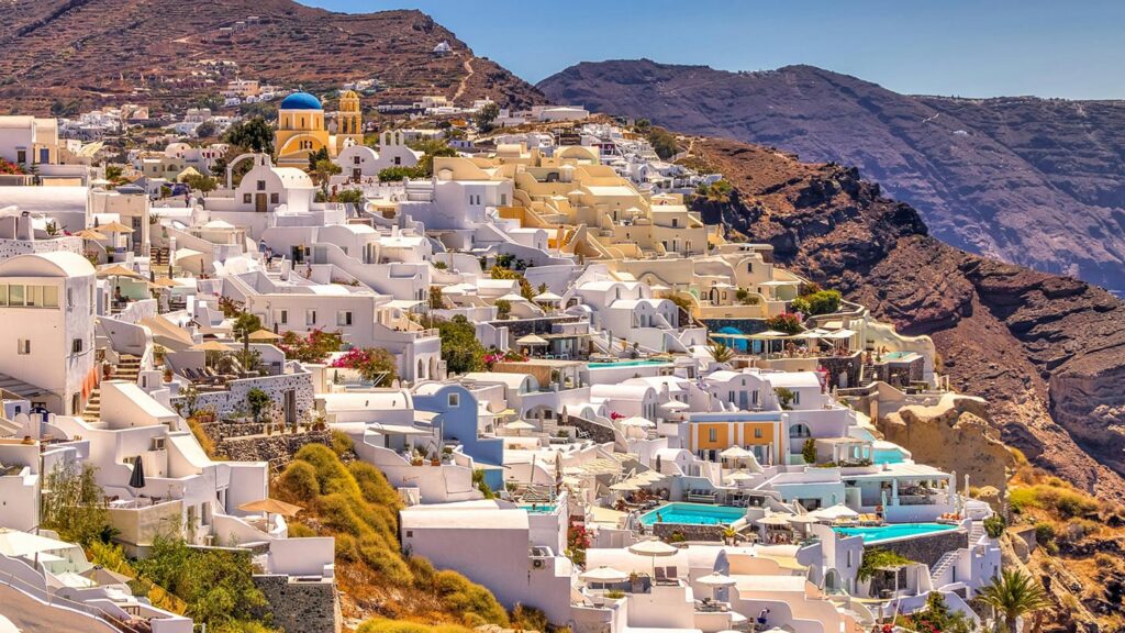 Bild av pittoreska pooler i Santorini, Grekland, omgiven av vita hus och berg.