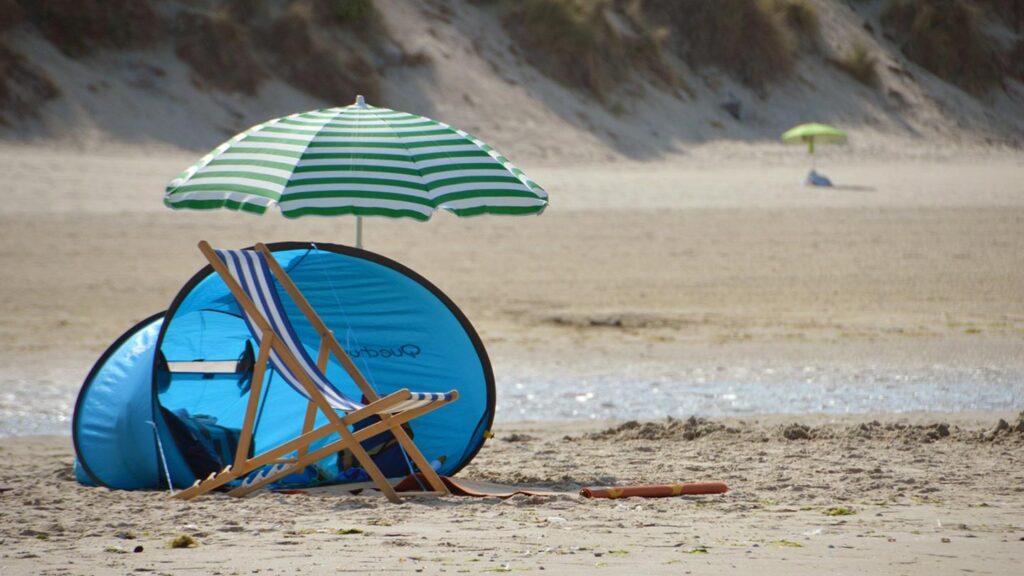 En solig strandscen vid Stella Beach i Cucq, Frankrike, med parasoll och stol.