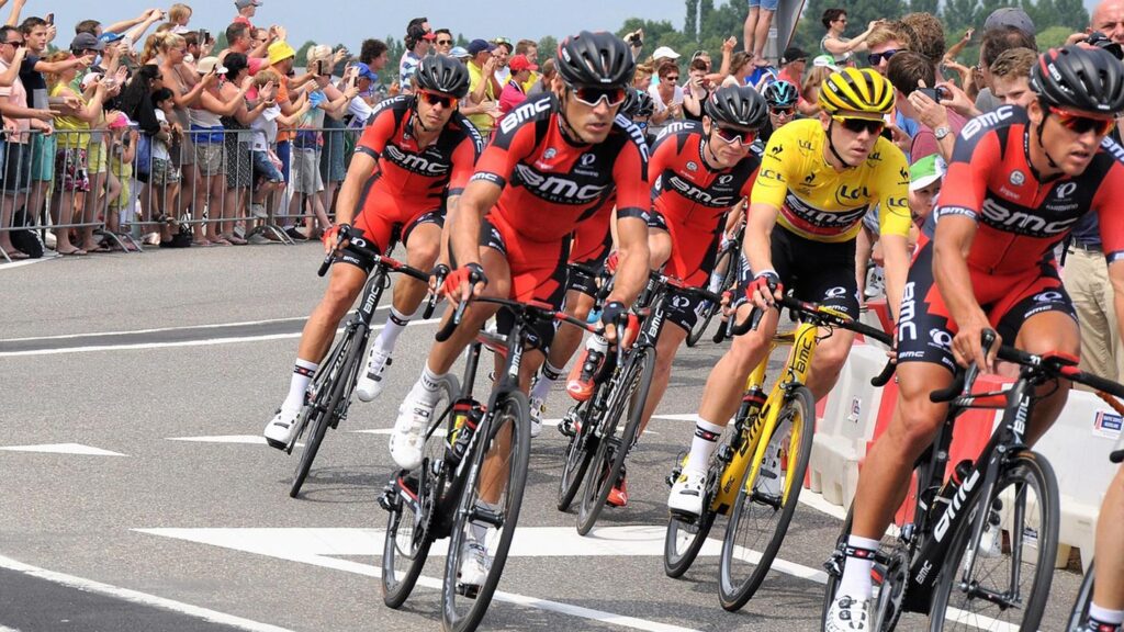 Cykelåkare tävlar i Tour de France i Frankrike, omgiven av applåderande åskådare.