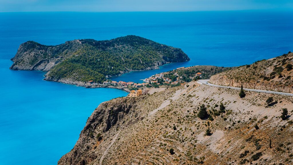 En väg leder ner mot den vackra byn Assos i Kefalonia, Grekland.