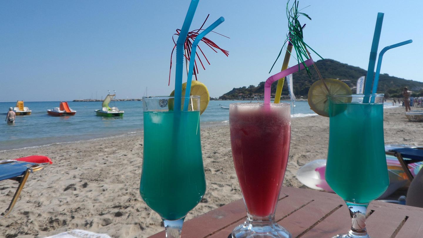 Tre färgglada cocktails på stranden i Zakynthos, Grekland, med sol och hav.
