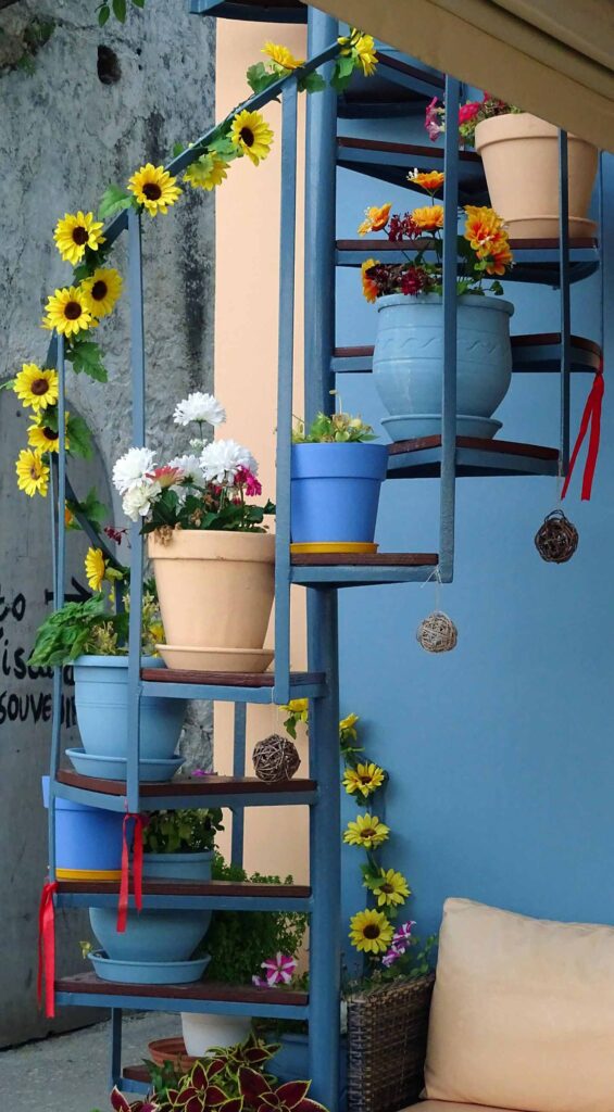 Färgglada krukor med blommor i Kefalonia, Grekland, på en spiraltrappa.