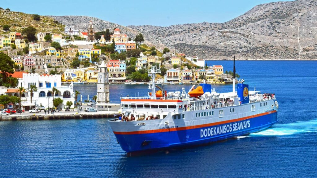 Färjan Dodekanisos Seaways närmar sig Symi ön med färgglada byggnader i bakgrunden.