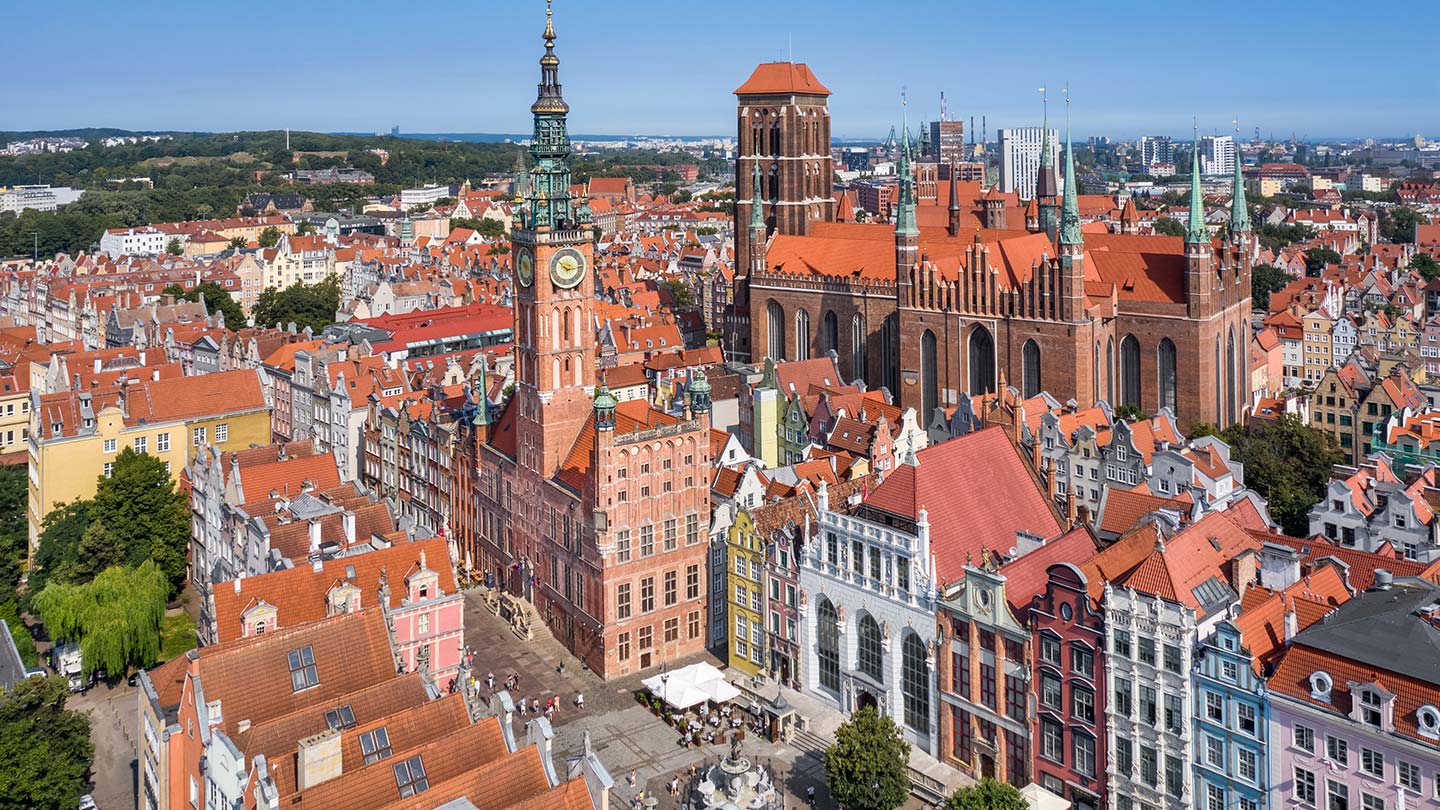 Flygfoto över det historiska rådhuset i Gdansk, Polen, omgiven av färgglada byggnader.