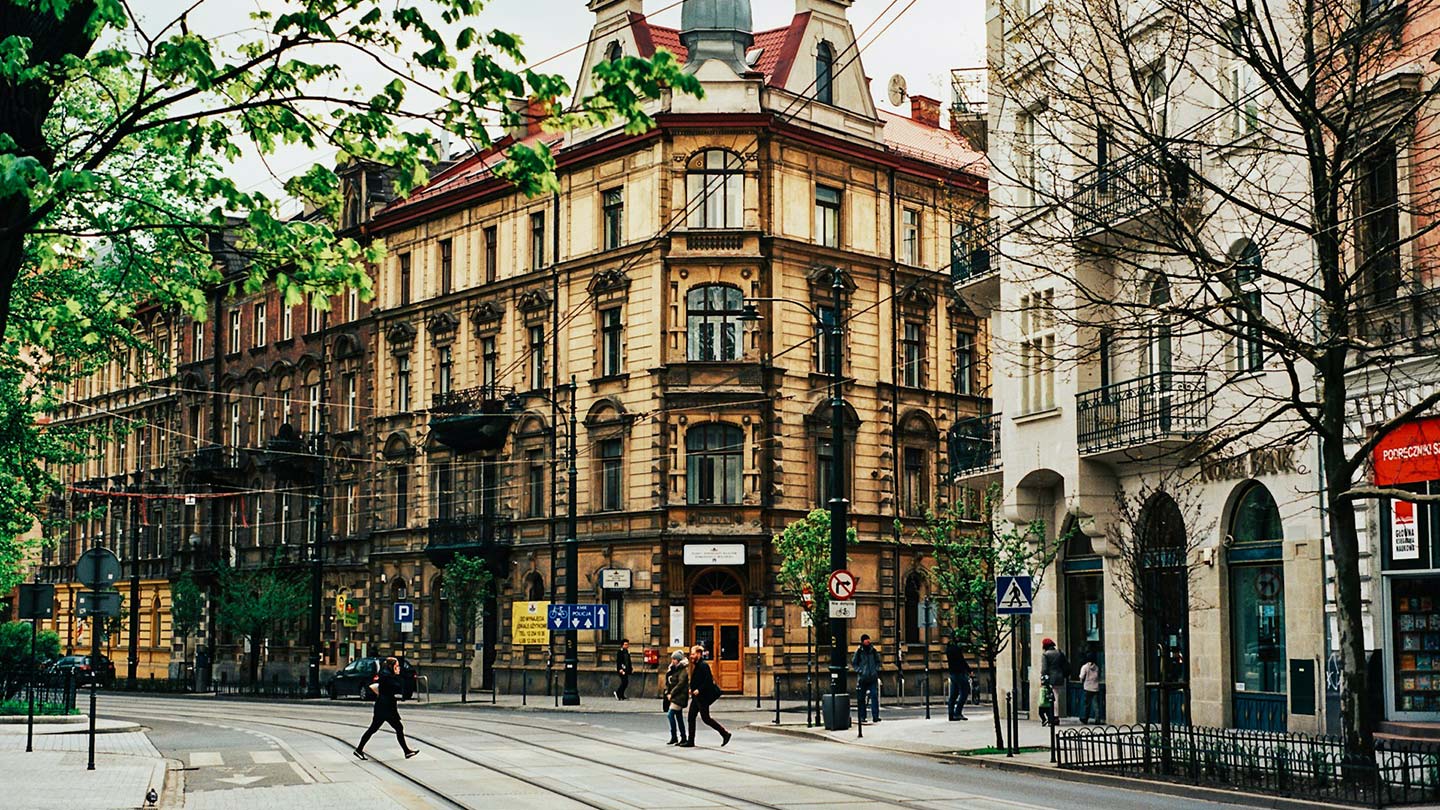 En livlig gata i Krakow, Polen, med vackra, gamla byggnader och träbussar.
