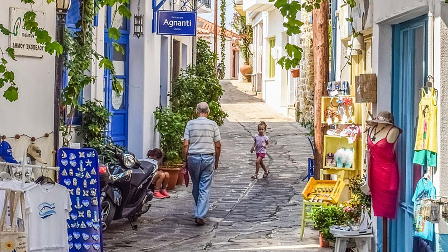 En charmig gata i Glossa, Skopelos, med äldre man och barn.