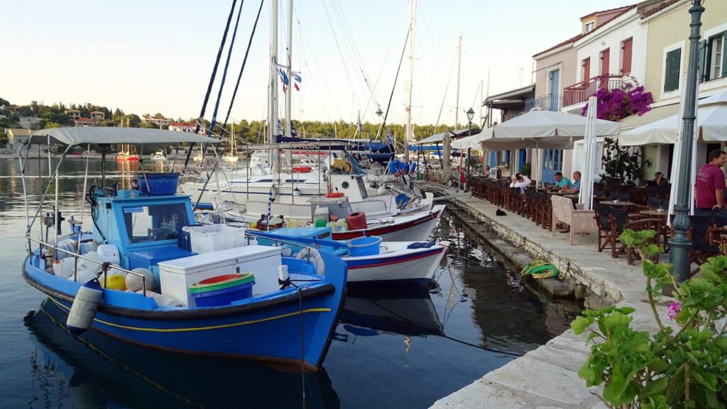 Hamn i Fiskardo, kefalonia, med uteservering och segelbåtar vid vattnet.