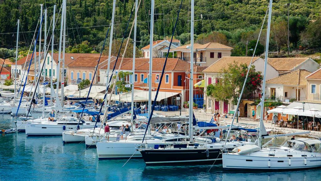 En livlig hamn på Kefalonia med segelbåtar och färgglada hus.