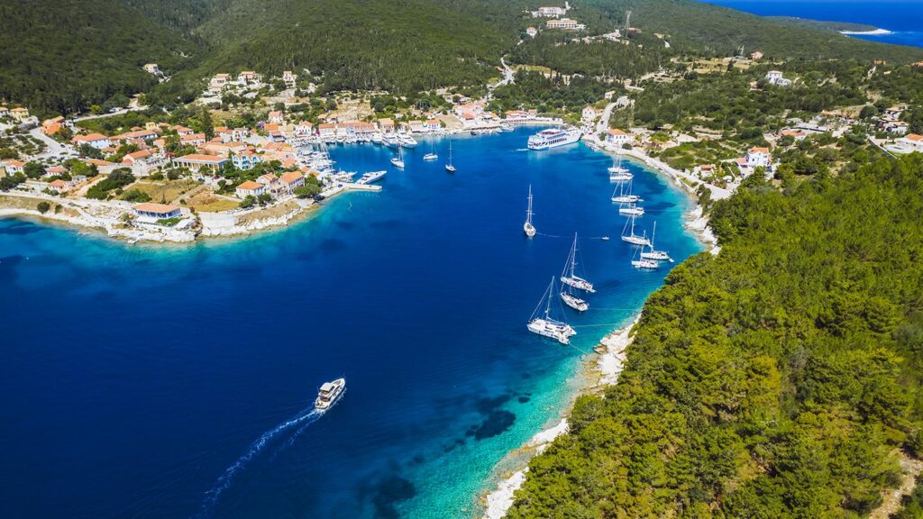 En vacker vy av hamnen i Fiscardo, Kefalonia, med segelbåtar och klart vatten.