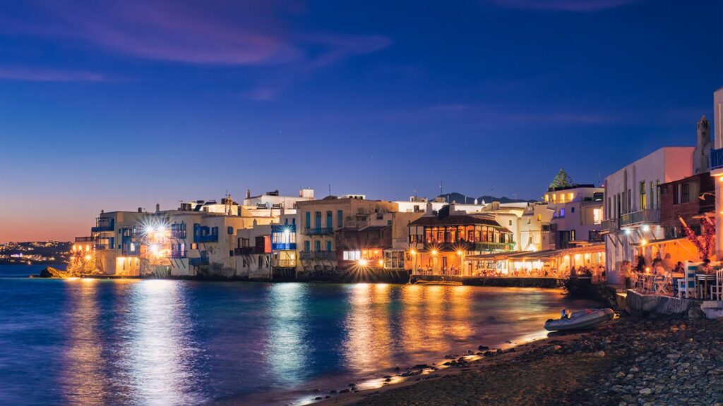 Bilden visar hamnen i Lilla Venedig, Mykonos stad, med färgglada hus vid vattnet.