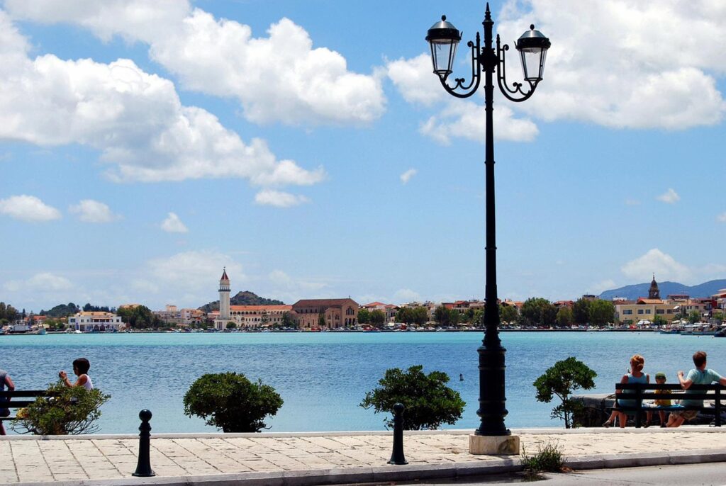 En vacker hamnpromenad i Zakynthos, med blått vatten och grönska.