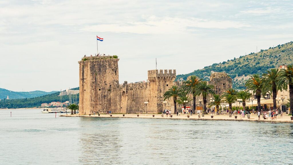 Kamerlengoborgen i Trogir, med palmträd och vacker utsikt över vattnet.