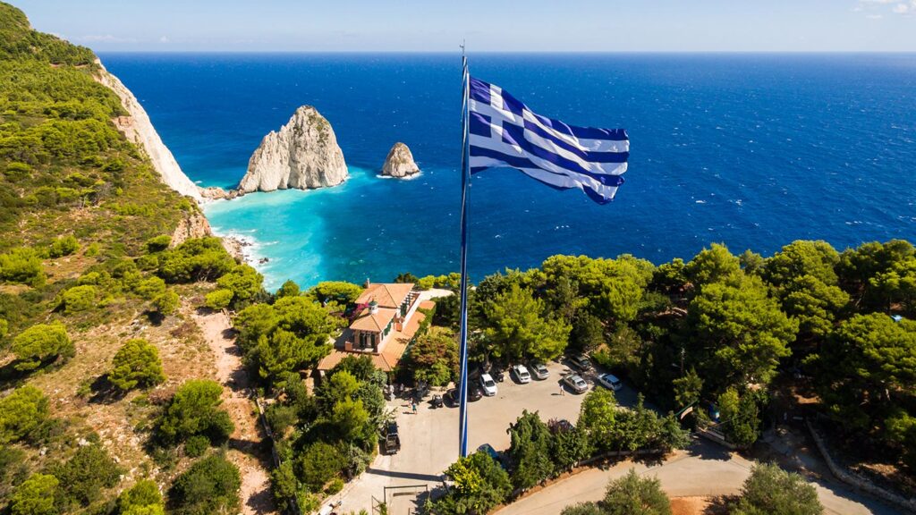 Utsikt över Keri på Zakynthos, med klart blått hav och grekisk flagga.