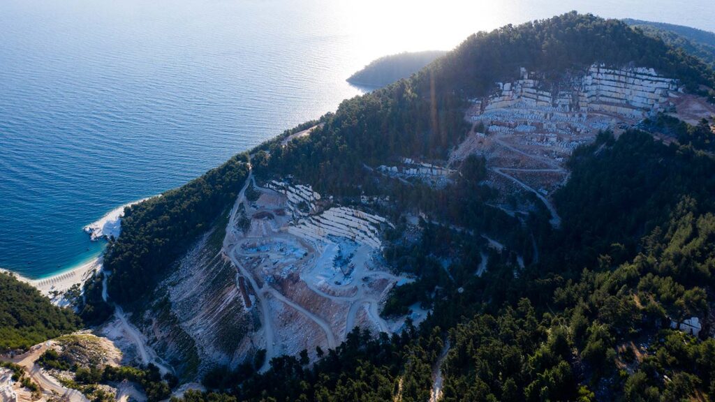Bild av ett marmorbrott på Thassos, Grekland, med hav i bakgrunden.