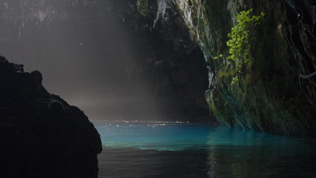Melissani grottan på ön Kefalonia i Grekland, med klart blått vatten och gröna klippor.