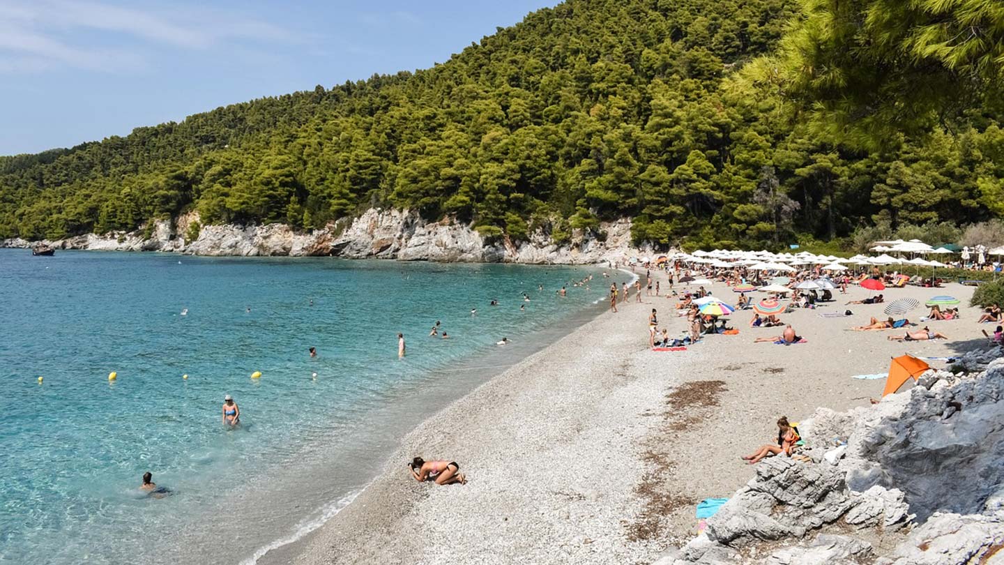 Milia Beach på Skopelos, vacker strand med solande människor och klart vatten.
