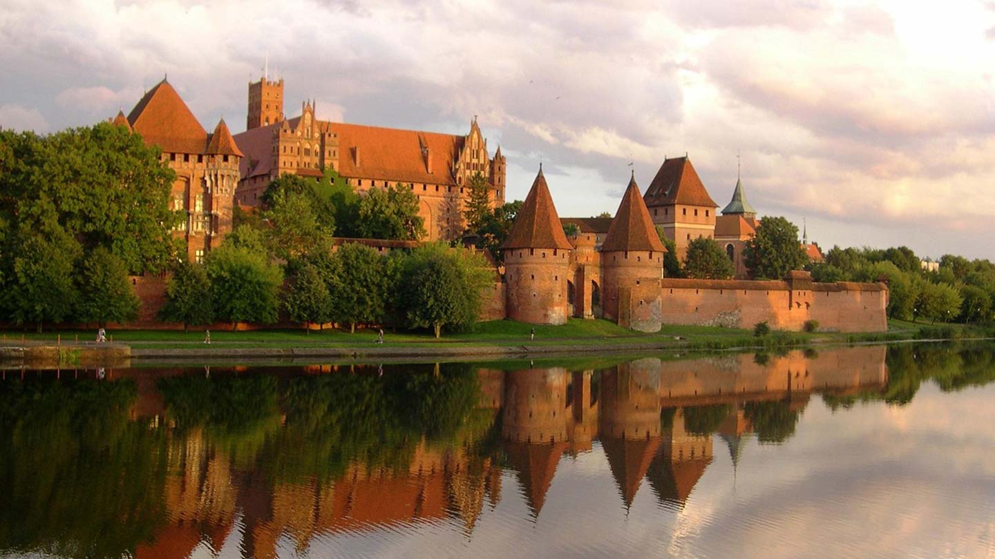 Ordensborgen i Malbork, Polen, reflekteras vackert i sjön vid solnedgången.