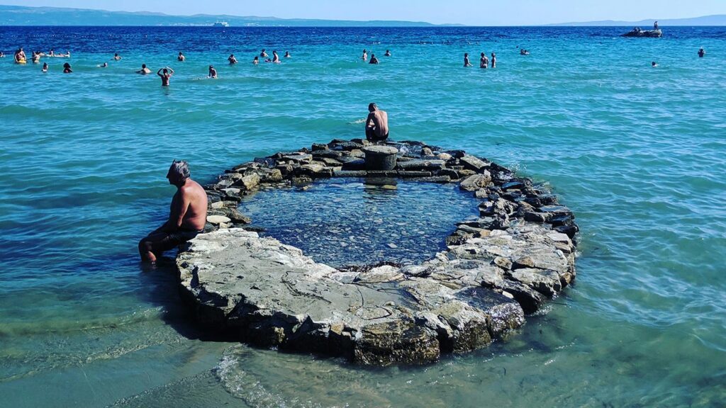 Bilden visar människor som badar i havet vid Poljička cesta, Split, Kroatien.