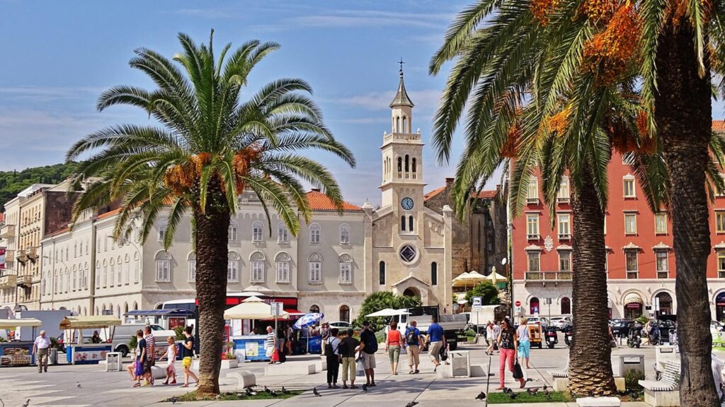 Ett livligt torg i Split, Kroatien, omgiven av palmer och historiska byggnader.