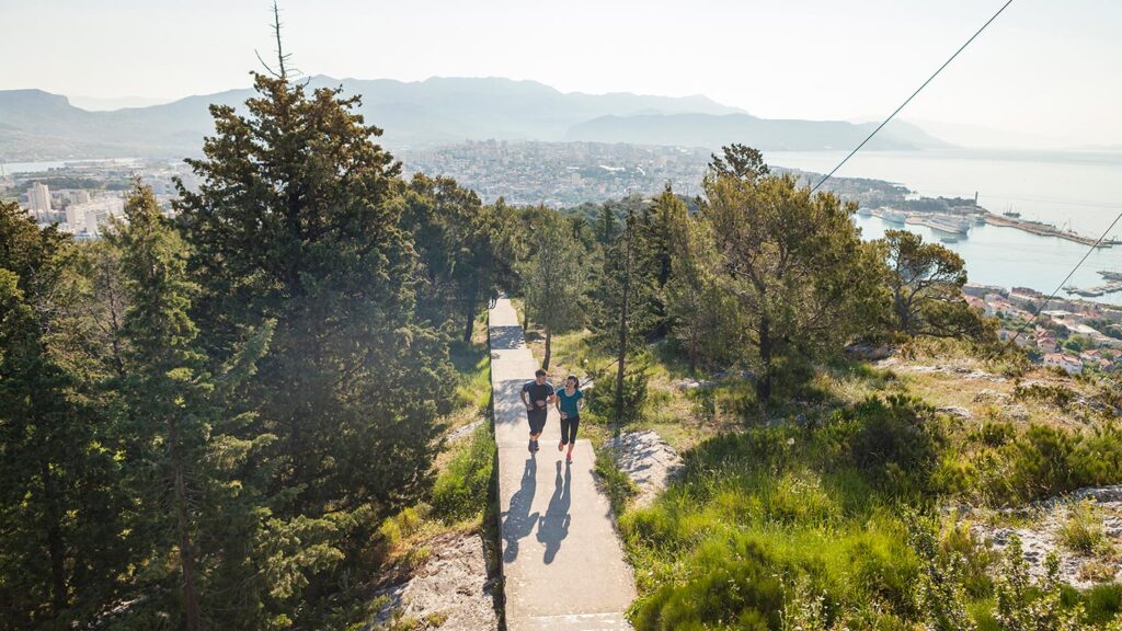 En löpare i parken i Split, Kroatien, omgiven av natur och stad.