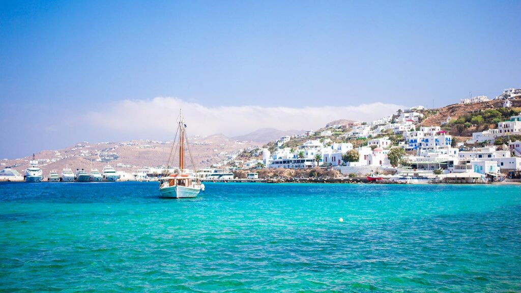 En vacker hamn i Mykonos med turkost vatten och vita byggnader.