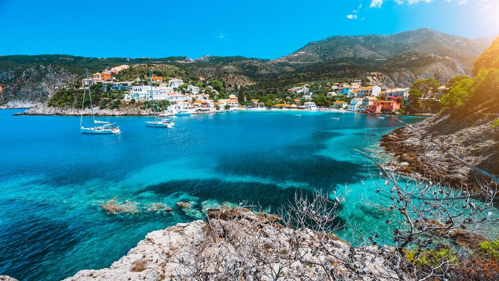 En vacker vy över Assos, Kefalonia, med turkost vatten och färgglada hus.